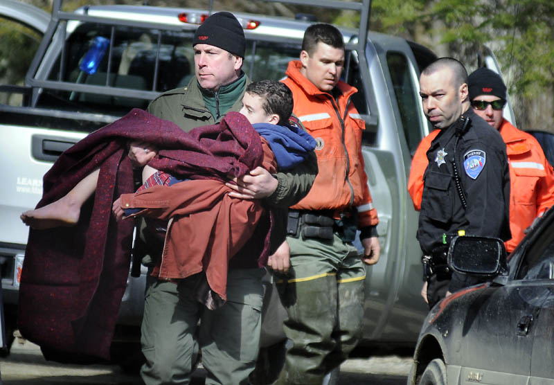 FOUND SAFE: Marine Patrol Officer Donaldson Boord carries 12-year-old Micah Thomas from a boat Thursday afternoon on the Eastern River in Dresden to an ambulance after a searcher discovered the boy in a smelt shack. Thomas had been missing since getting off a school bus Wednesday afternoon and was the focus of a intense search by several law enforcement agencies. The boy, according to Lt. Kevin Adams of Maine Warden Service, is expected to be fine.