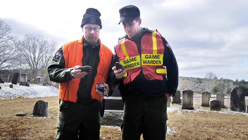 COMPARING NOTES: Game Wardens Steve Couture, left, and Justin Fowlie compare GPS data Thursday morning while searching near a cemetery in Dresden for 12-year-old Micah Thomas.