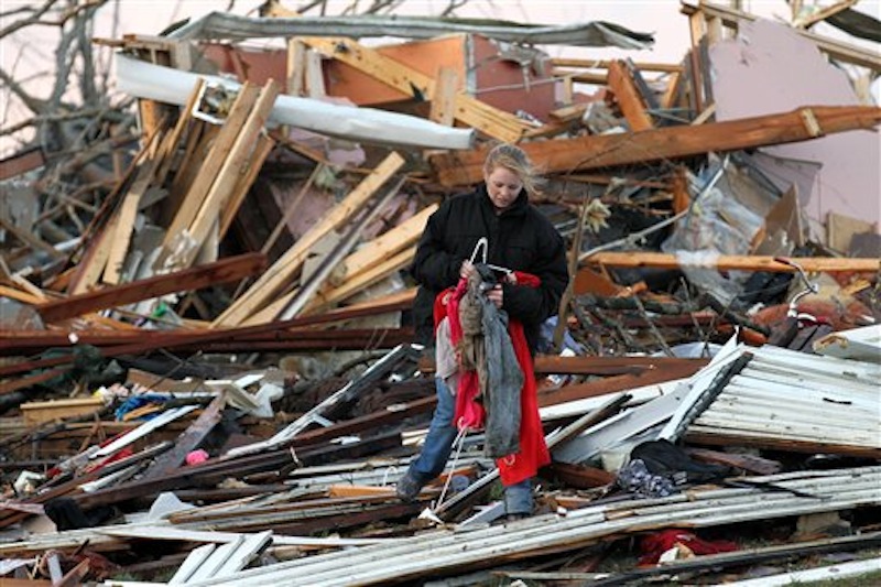 In this photo provided by SWAT Chasers via the Indianapolis Star, a woman salvages belongings from her home that was destroyed in Henryville, Ind., Friday, March 2, 2012, after a series of powerful tornadoes tore through southern Indiana, killing at least 32 people and leaving several small towns in ruin. (AP Photo/SWAT Chasers, Chris Bergin via the Indianapolis Star)