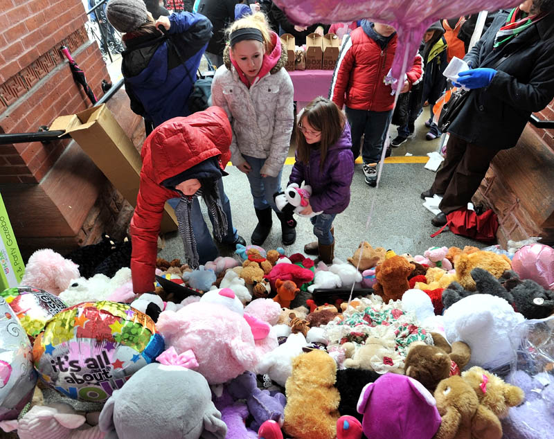 LOTS OF BEARS: Ashley-Ann Ferris, left, places a teddy bear on the steps of Waterville City Hall with her cousin Skylar Starbird, 12, center, and daughter Hailie Hotham, 7, during a vigil for missing toddler Ayla Reynolds at Castonguay Square in downtown Waterville on Saturday.
