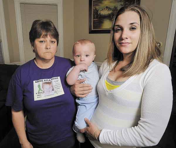 STILL IN LIMBO: Trista Reynolds holds her 1-year-old baby, Raymond Fortier, with her mother, Becca Hanson, on Wednesday in Portland. Reynolds says she continues to pray for Ayla’s safe return but needs answers — good or bad — about her daughter’s fate.