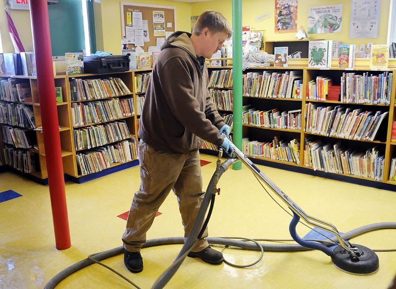 Servpro employee Blake Clements buffs the floor Monday in the children’s section of Bailey Public Library in Winthrop after it flooded when a pipe burst. The children’s section will be closed about a week to repair the damage.