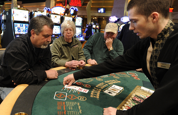 Shawn Hollobaugh, right, deals cards to Tom Gagne of Bangor, left, as others watch during a game of three-card poker at the Hollywood Casino Hotel and Raceway in Bangor today.