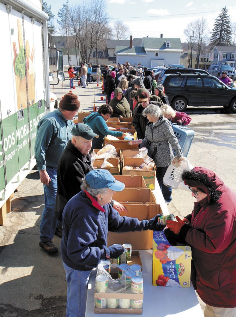 Volunteer Norma Shaw hands some food to Joanne Jones of Vassalboro on Friday in Augusta. The Augusta Food Bank used the Good Shepard Food Bank's food mobile, set up in a parking lot near Lithgow Library on State Street, to distribute 9,000 pounds of food to 347 families.