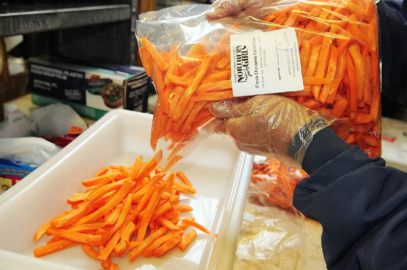 Dr. Harold Gram weighs carrots as he and other volunteers split up produce from large bags that came from farmers into smaller orders for customers on market pickup day last week.