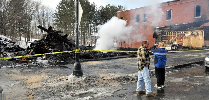 GONE: Nelson and Tracy Dube survey the scene on Wednesday of the still-smoldering remains of a building on Main Street in Madison that was destroyed by fire Tuesday night.