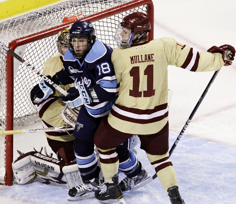 GRINDING OUT SOME SPACE: Maine’s Jon Swavely, center, is sandwiched between Boston College goaltender Parker Milner, left, and forward Pat Mullane during the first period of the Hockey East tournament championship game Saturday night in Boston. Maine lost 4-1