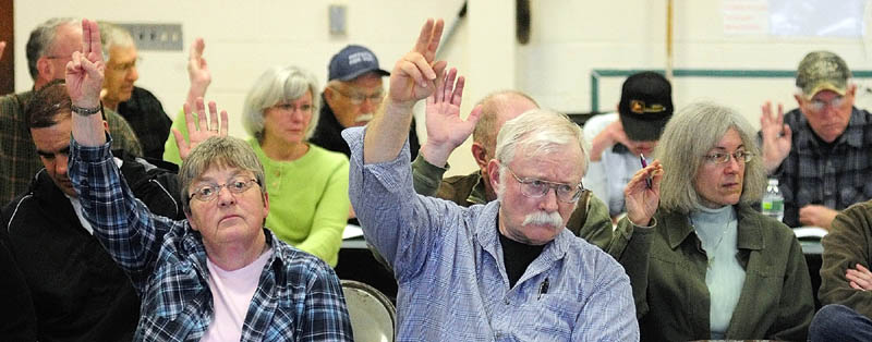 Residents vote for a question during the annual town meeting on Saturday morning at the Pittston School.