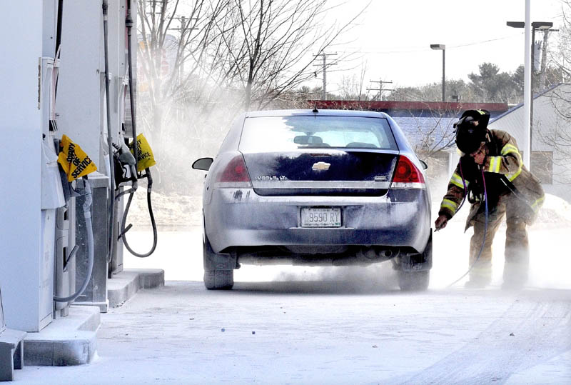BLOW OUT: Skowhegan Fire Department Capt. Rick Caldwell wears protective gear while using an air hose to blow off fire suppressant powder that covered vehicles, customers and the ground at the Irving Circle K store in Skowhegan on Sunday.