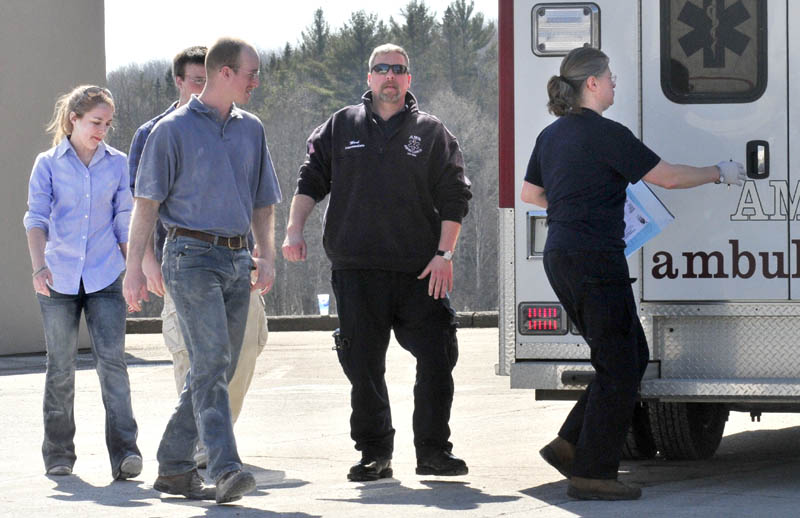 EXAMINED: Three people at left including customer Becca Mattingly are led to an ambulance to be examined after they were covered with a fire suppressant powder that was released and covered people, vehicles and the roadway at the Irving Circle K store in Skowhegan on Sunday. Mattingly said later, "I was shocked and scared at first, but I'm alright."