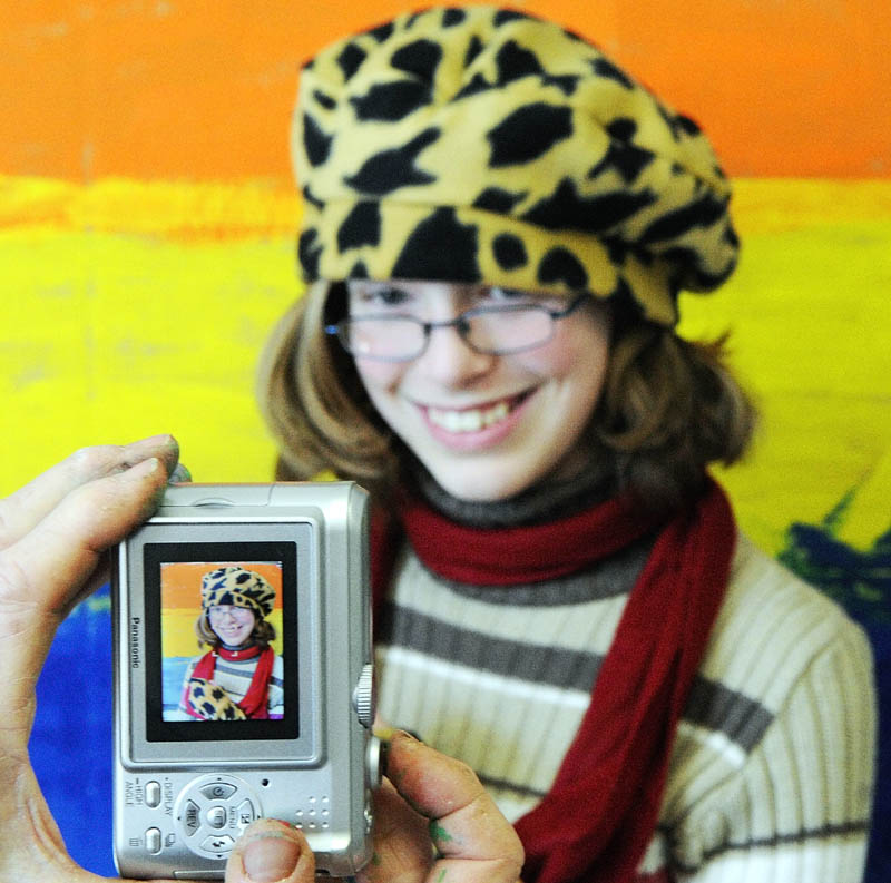 Betsy Allen-McPhedran snaps a photo of Abigail Frank standing if front of the back drop she painted while wearing the hat she made for art class on Tuesday afternoon at Readfield Elementary School.