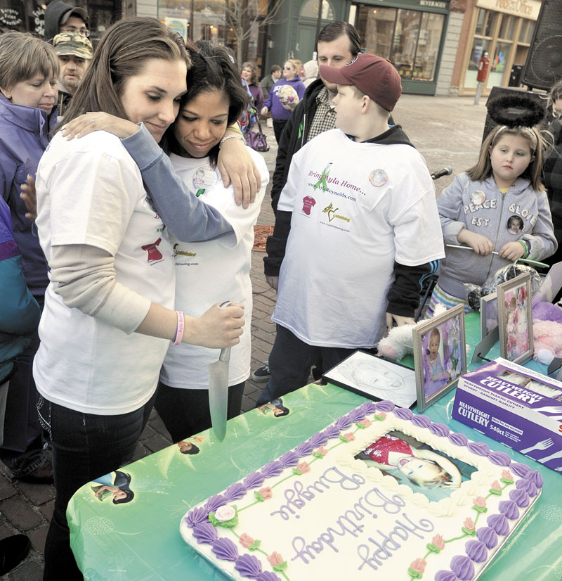 Trista Reynolds, left, shares a hug with stepsister Whitney Reynolds before cutting a cake at an event in support of Ayla Reynolds Wednesday in Portland on Ayla’s second birthday.