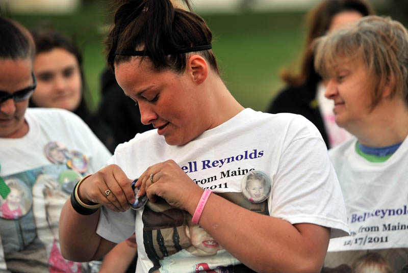 VIGIL: Ashley Pouliot, center, pins an Ayla Reynolds button to her T-shirt before a vigil for the missing toddler in Waterville on Thursday.