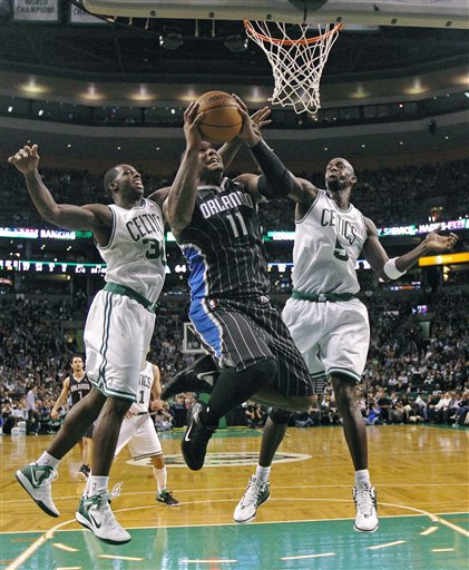 Boston Celtics forwards Brandon Bass, left, and Kevin Garnett, right, combine to try to stop Orlando Magic forward Glen Davis (11) on a drive to the basket during the second half of an NBA basketball game in Boston, Wednesday, April 18, 2012. The Celtics won 102-98. (AP Photo/Charles Krupa)