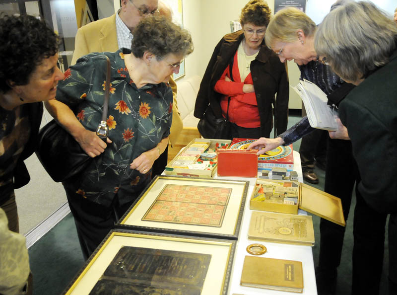 People examine books and games by Vienna native Milton Bradley following a Wednesday lecture by historian David Richards on the inventor's life at the Maine State Museum in Augusta.