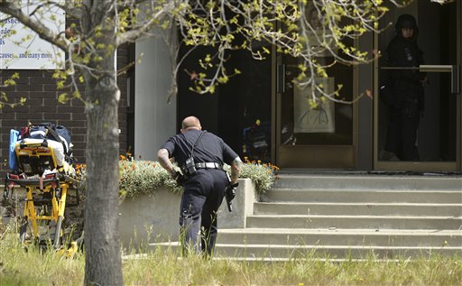 An Oakland police officer approaches the entrance to Oikos University in Oakland, Calif., today. A suspect is in custody in a shooting attack that has left at least seven people dead.