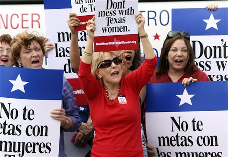 In this March 6, 2012 file photo Mary Green, Peg Armstrong and Jan Perrault hold up signs during Women's Health Express, a bus event held in San Antonio, Texas, to protest the attempt to cut Planned Parenthood out of the state's Women's Health Plan. Federal Judge Lee Yeakel ruled Monday there is sufficient evidence a law barring Planned Parenthood from participating in the Texas' Women's Health Program in unconstitutional and stopped the state from banning the organization from receiving state funds. (AP Photo/San Antonio Express-News, Helen L. Montoya, File)