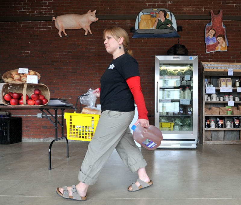 CARRYING HER SHARE: Gwynne Dunphy picks up her share of produce, milk and cider Wednesday as part of the Pickup program, a new community supported agriculture program at the Grist Mill in Skowhegan.