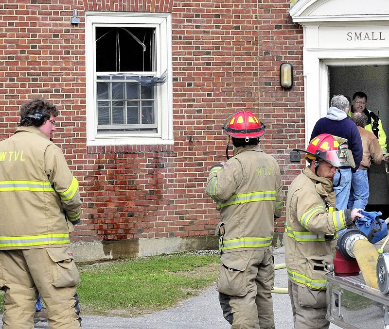 FIRE: Waterville firefighters gather outside the East Quad dormitory at Colby College near a dorm room window that was broken after fire from an unattended lit candle caused damage to the room on Thursday.