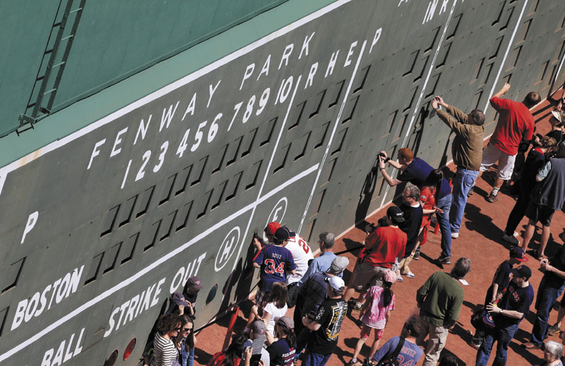 HISTORIC FENWAY PARK: People view the scoreboard section of the Green Monster left field wall Thursday during an open house at Fenway Park in Boston. The Red Sox will celebrate the 100th anniversary of their first-regular season game today when they host the New York Yankees.