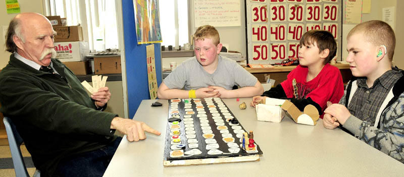 LEARNING GAME: Special Education teacher Kevin McShane works with Cascade Brook School students from left, Zakary Lorom, Austin Thibault and Cedar Seantea with a prototype of his math-skill learning game titled "Smiling Sam the Game" recently at the Farmington school.
