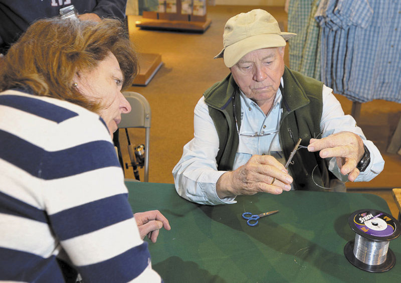 LIKE THIS: Lefty Kreh is quick to teach fishing intricacies, including showing Norma Nardone of Kennebunk how to tie a 6-loop clinch knot with forceps during a visit to L.L. Bean.