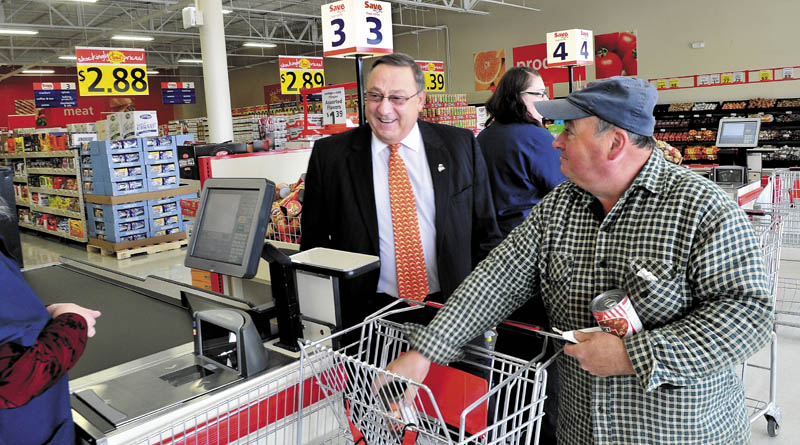 CHECK IT OUT: Gov. Paul LePage tours the new Save-A-Lot grocery store that opened Wednesday in The Concourse in Waterville as customer John Roy’s groceries are rung up by a cashier.