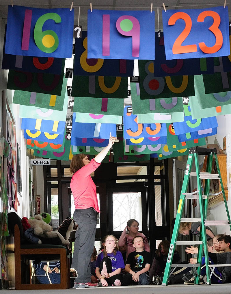 District Math Coach Sarah Caban points at an equation hanging from the ceiling during a lecture on Wednesday morning at Mount Vernon Elementary School. She and art teacher Dona Seegers co-taught a math and art class for third-graders under the Math Gate banners in the school's main hallway.