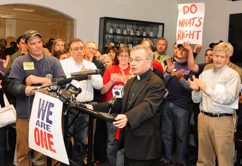 People cheer as the Rev. Mike Seavey, a Catholic priest, speaks during a news conference held by opponents of L.D. 309 in the State House on Wednesday in Augusta. The so-called right-to-work bill was to come up for a vote by a legislative committee.