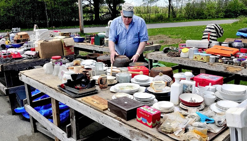MAKE AN OFFER: Philip Goodell sets up merchandise on tables for the annual 10-mile yard sale at his home on the West Ridge Road in Cornville for this weekend's annual event.