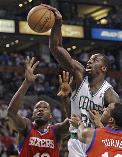 Boston Celtics' Brandon Bass, center, reaches for a rebound against Philadelphia 76ers defenders Elton Brand, left, and Evan Turner during the first quarter of Game 5 in their NBA basketball Eastern Conference semifinal playoff series in Boston, Monday, May 21, 2012. (AP Photo/Charles Krupa)