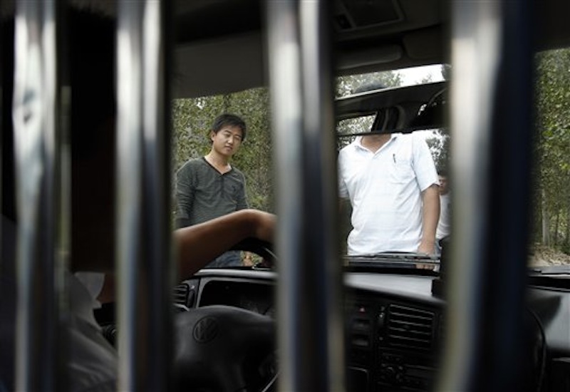 In this Sept. 9, 2010 file photo, unidentified men block a journalist's vehicle from entering Dongshigu Village where blind activist Chen Guangcheng was locked down, in eastern China's Shandong province. While China has long been a police state, controls on these non-offenders mark a new expansion of police resources at a time the authoritarian leadership is consumed with keeping its hold over a fast-changing society. (AP Photo/Andy Wong, File)