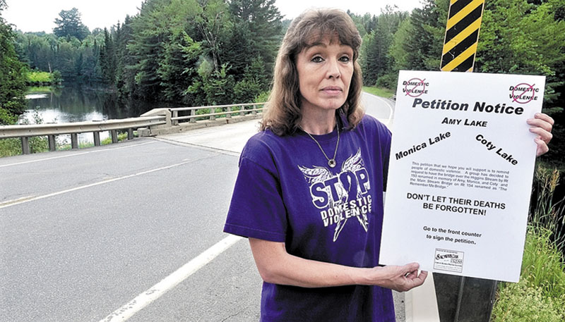 Sandra Mitchell, seen holding a petition at the Higgins Stream bridge in Harmony in July 2011, is stepping up her fight against domestic violence with a fundraising drive to add memorial gardens at several bridges that she worked to have renamed to honor past victims of violence.
