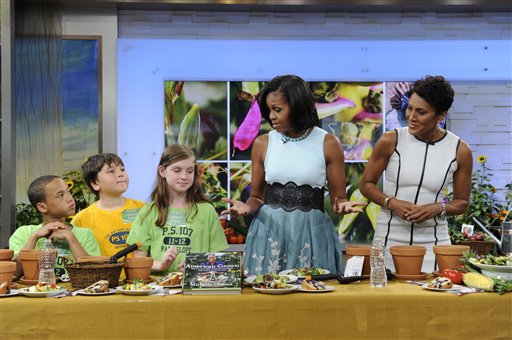 This image released by ABC shows host Robin Roberts, right, looking on as first lady Michelle Obama talks with students from PS 102 and 107 from the Brooklyn borough of New York, on "Good Morning America," Tuesday, May 29, 2012 in New York. Obama discussed a variety of topics including her new book "American Grown: The Story of the White House Kitchen Garden and Gardens Across America," which promotes healthy eating. (AP Photo/ABC, Ida Mae Astute) GM12