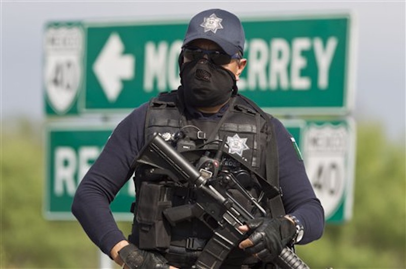 A federal policeman guards the area where dozens of bodies, some of them mutilated, were found on a highway connecting the northern Mexican metropolis of Monterrey to the U.S. border found in the town of San Juan near the city of Monterrey, Mexico, Sunday, May 13, 2012. (AP Photo/Christian Palma)