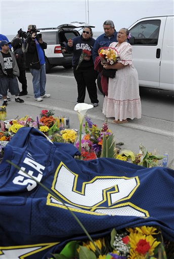 Family members of former NFL star Junior Seau put flowers at a memorial in the driveway of his home on Thursday in Oceanside, Calif.
