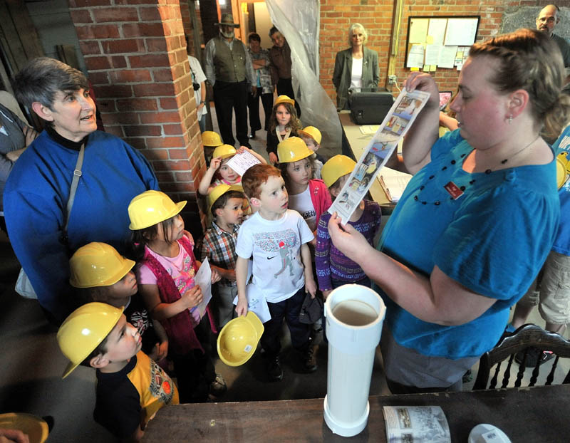 FOR FUTURE READERS: Angie Herrick, right, the children's librarian at Skowhegan Public Library, shows local children some of the artifacts placed into the time capsule that will be sealed in to the ceiling of the basement at the library on Tuesday. The children also wrote letters and drew pictures that will be placed in the capsule.