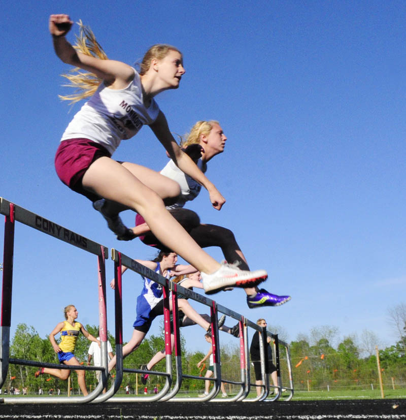 UP AND OVER: Monmouth Academy hurdlers Tiffany Pease, left, and Melissa Brassard go stride for stride in the 100-meter hurdles during a meet Friday evening at Alumni Field in Augusta.