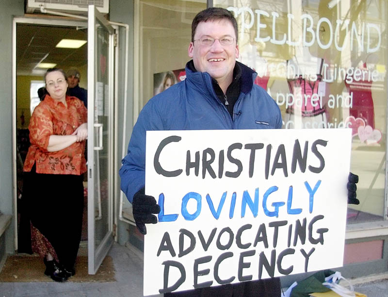 NOT SPEAKING: Owner Felicia Stockford, left, stands in the door of Spellbound Lingerie watching a small group of protesters organized by Michael Hein, right, on Water Street in Augusta in this 2006 file photo.