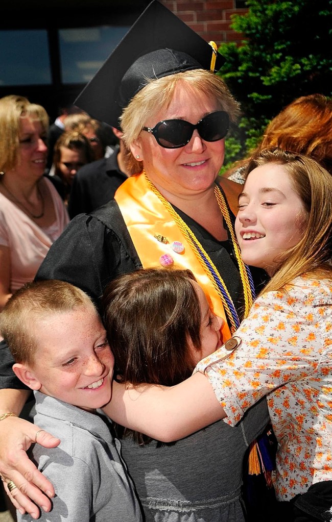 Graduate Nancy Martin gets a hug from her nephew Dylan Murphy, left, niece Dessie Murphy and daughter Carrie Martin after graduating from Kennebec Valley Community College on Saturday at the Augusta Civic Center.