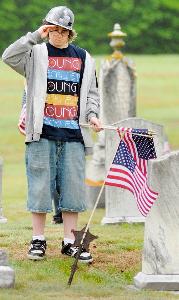 Colby Russell-Leo salutes after placing a flag in a holder in front of the gravestone of a veteran Friday at Plains Cemetery in Litchfield. Members of the American Legion William R. Bold Post 181, along with 21 Oak Hill Middle School students, placed flags on 466 veteran graves. There will be a ceremony at the cemetery as part of the Memorial Day parade starting at 9:30 a.m. Monday.