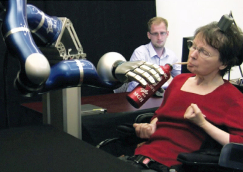 Cathy Hutchinson of East Taunton, Mass., sips a drink held by a robotic arm during a test at a long-term care residence for adults with neurological disease in Dorchester, Mass.