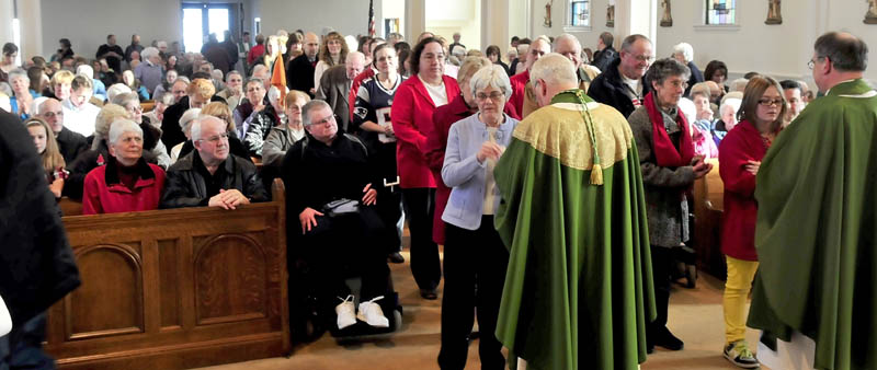 FINAL MASS: The Most Rev. Richard J. Malone, center, Bishop of Portland, conducts Communion services during the final Mass in February at St. Francis de Sales Church in Waterville. Some residents aren't happy with plans to demolish the church so that a housing project can be built in its place.