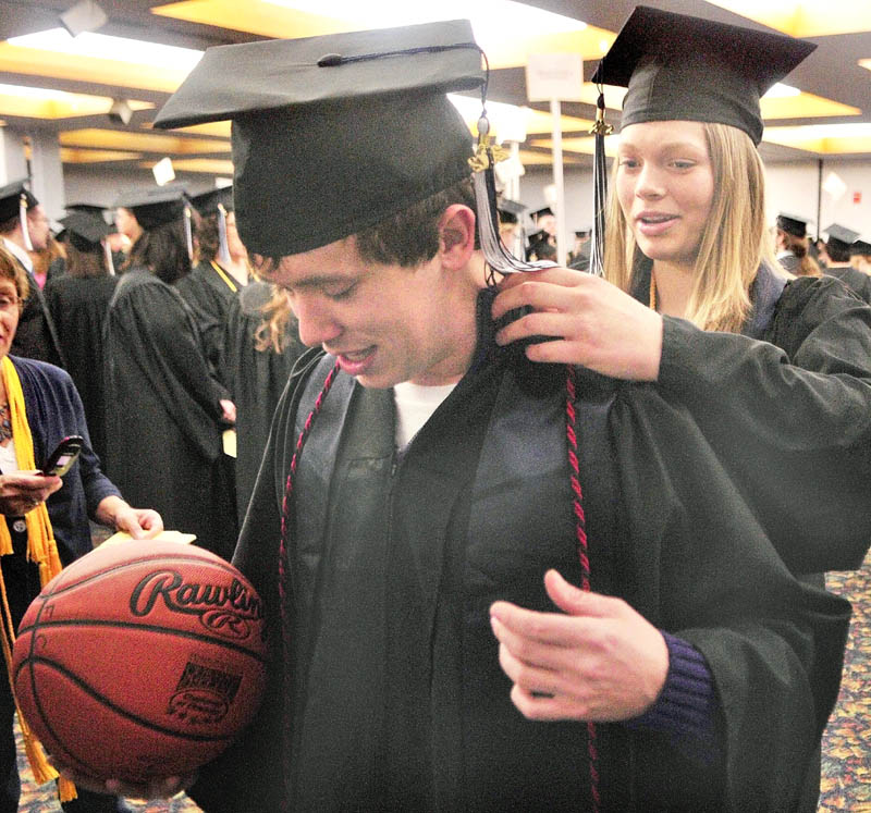 Marty Campbell, of Whitefield, left, gets some help straightening out his sash and cord from fellow graduate Katie Poirier, of Harmony before the University of Maine at Augusta graduation exercises on Saturday morning in the Augusta Civic Center. They had both played for the University's basketball teams.