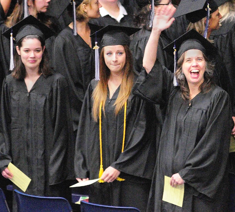 Shelley Vermillion, of Gardiner, right, waves to her family after marching into the Augusta Civic Center for the University of Maine at Augusta graduation exercises on Saturday morning.