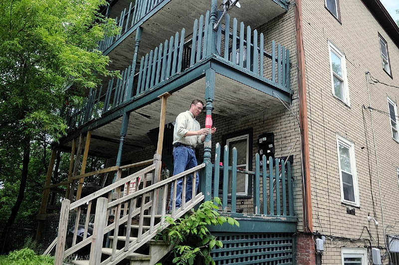 UNSAFE CONDITIONS: Augusta code enforcement officer Rob Overton tapes a notice on the deck at 11 State Street that wooden stairs and deck entrance to three apartments in the building is unsafe. Tenants in the units were ordered to relocate.
