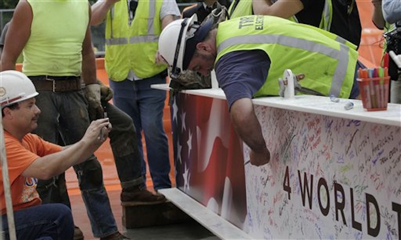 A construction worker signs the ceremonial last beam before it is hoisted to the top of Four World Trade Center, Monday, June 25, 2012. The 72-floor, 977-foot tower is scheduled to open late next year. It's expected to be the first tower completed on the 16-acre site since the 9/11 attacks. (AP Photo/Mark Lennihan) 9/11,ground zero,Sept 11,Silverstein