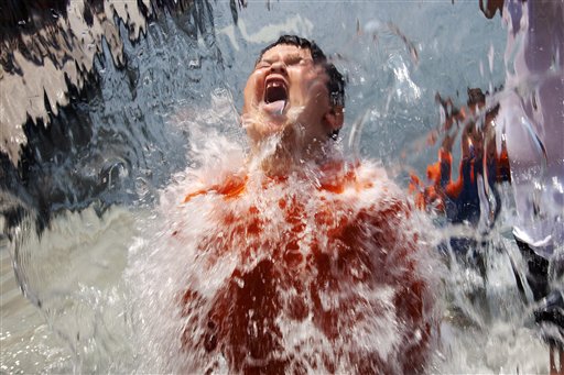 Lucas Olivo, 6, of Cheverly, Md., opens his mouth wide while running through a wall of water at Yards Park in Washington, D.C., today.