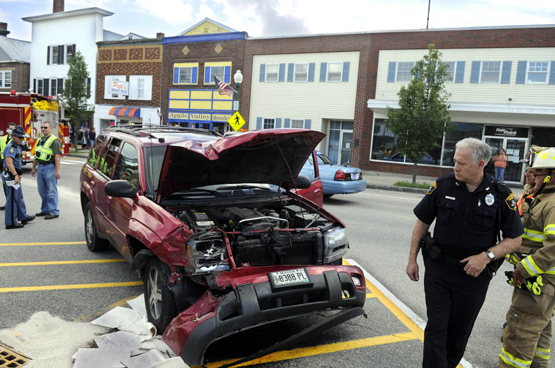 Police and firefighters inspect a sport utility vehicle that crashed Thursday in downtown Winthrop while being pursued by Maine State Police. State trooper Dane Wing arrested Glen Harrington after police said he crashed into two trucks and fled on foot.