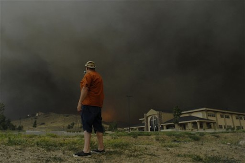 A man stops quickly to get some video before running away from approaching flames of the Waldo Canyon Fire as it raced down into western portions of Colorado Springs, Colo. on Tuesday, June 26, 2012 leaving a trail of destruction and burning homes and buildings in its path. Heavily populated areas in the fire's path have been affected. (AP Photo/Bryan Oller) Bryan Oller;Waldo Canyon Fire;Colorado Springs Fire;forest fire
